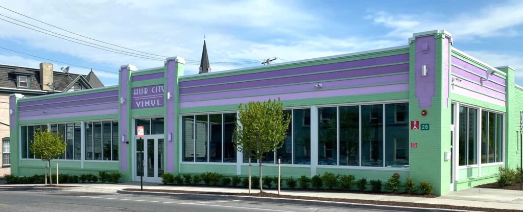 A pastel green and purple building with large windows, labeled 