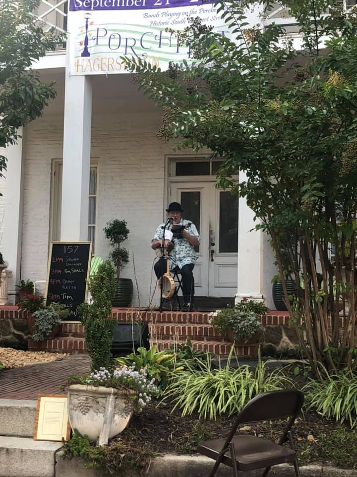 A banjo player sitting on a porch during the Hagerstown Porch Fest.