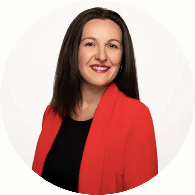 A woman with straight, dark brown hair wears a bright red blazer over a black top, smiling at the camera against a plain white background.